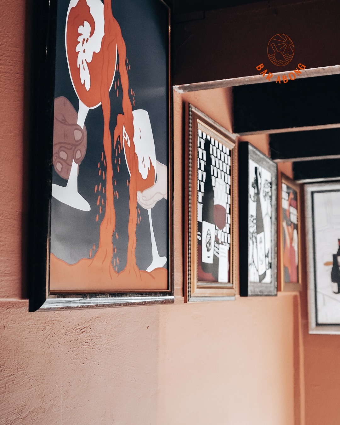 Framed wine artwork on a terracotta wall beneath the Bar Abong logo