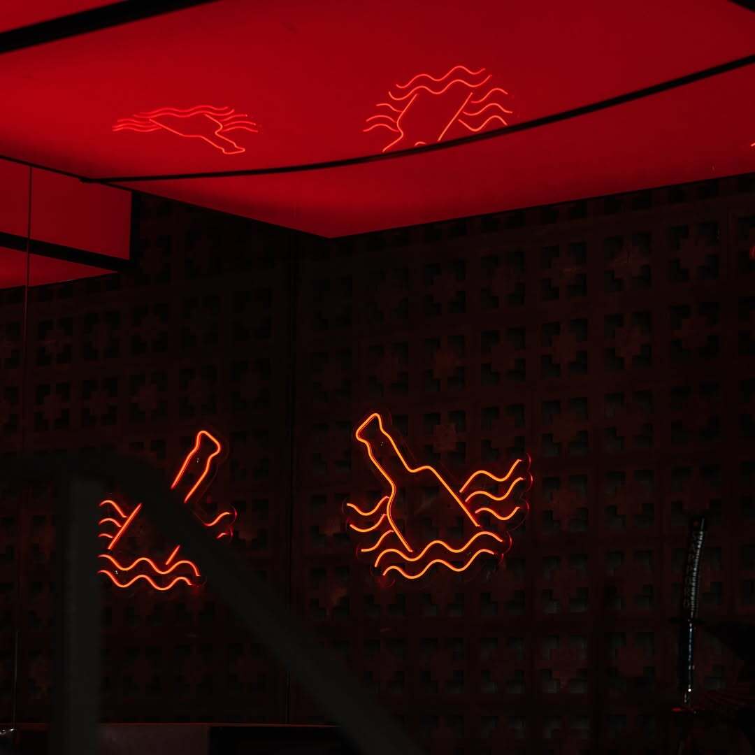 Red neon bottle and fish signs on the breeze-block wall of Bar Abong's interior